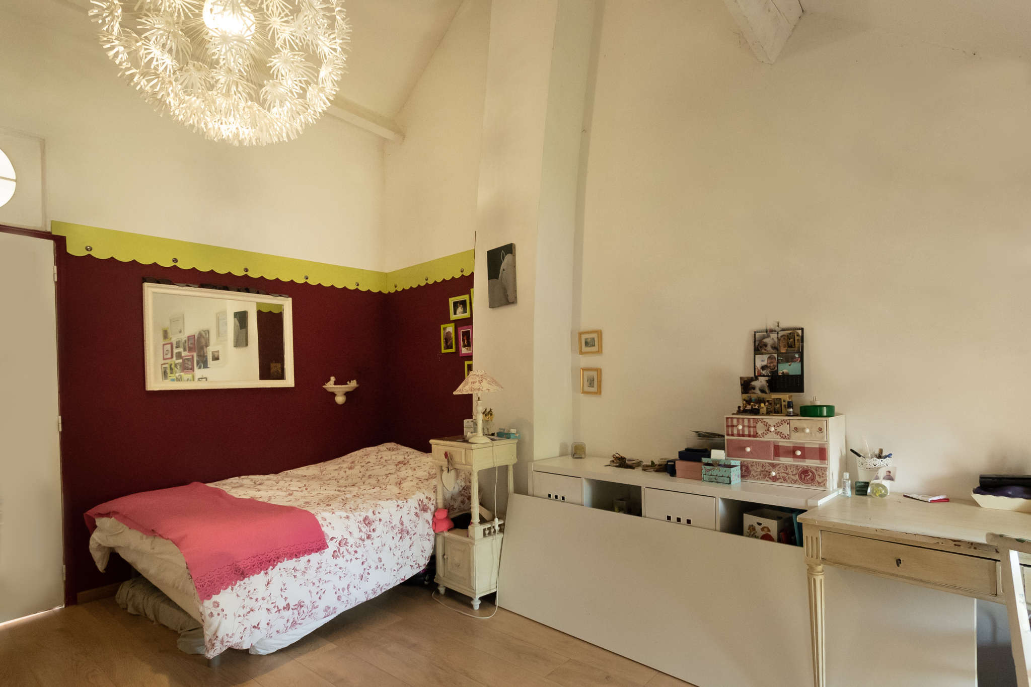 Chambre avec lit, décoration simple et lumineuse, murs rouges et blancs, meubles en bois.