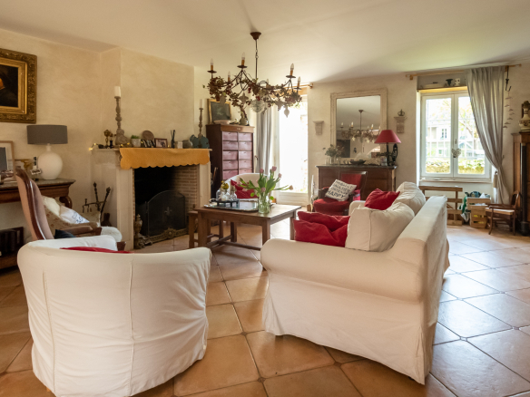 Intérieur d'une maison familiale avec un grand séjour, cheminée, et mobilier chaleureux.