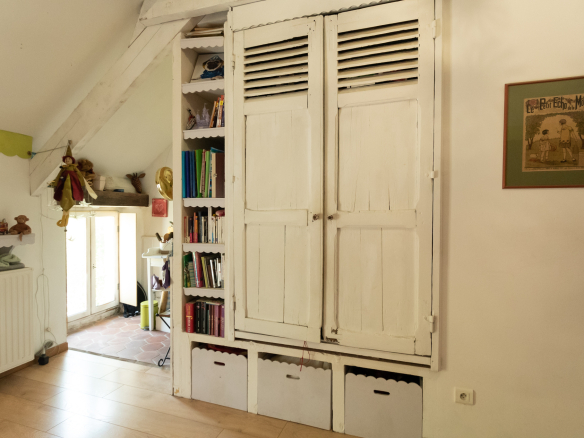 Intérieur d'une maison avec un meuble de rangement blanc et des étagères remplies de livres.