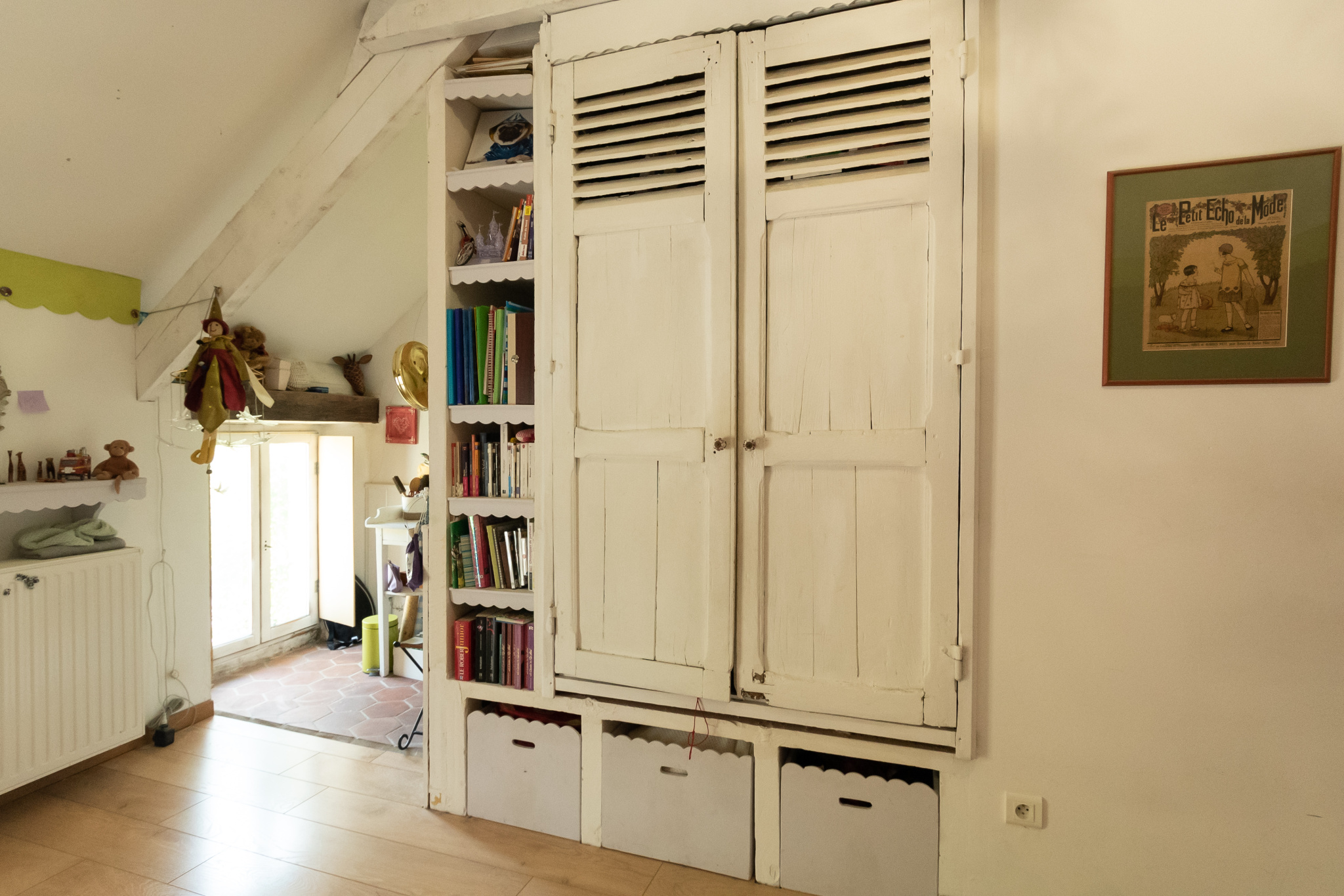 Intérieur d'une maison avec un meuble de rangement blanc et des étagères remplies de livres.