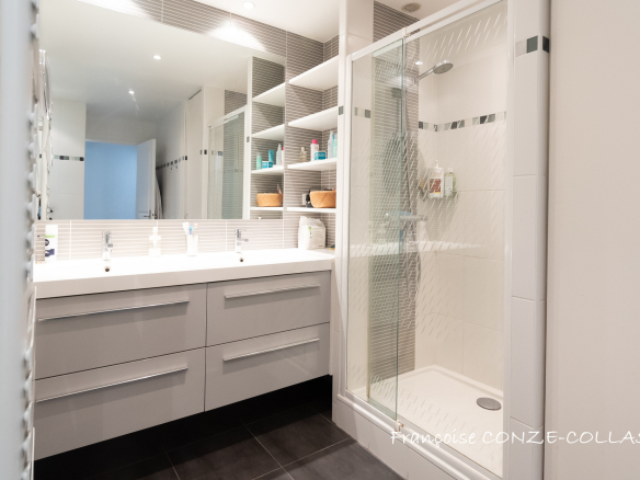 Salle de bain moderne avec douche, lavabo et rangements, appartement familial à Levallois-Perret.
