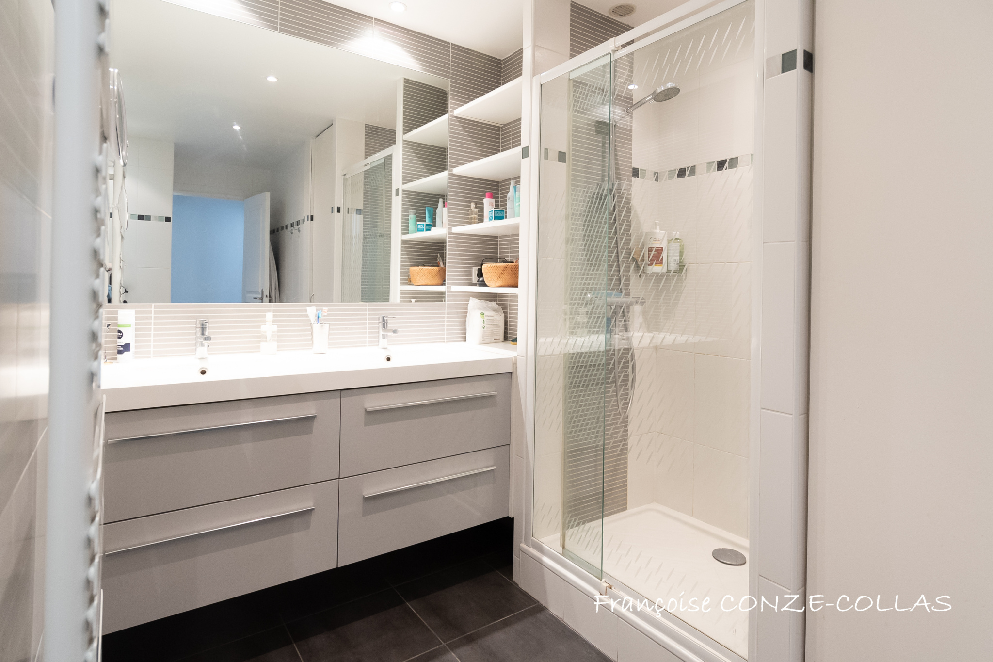 Salle de bain moderne avec douche, lavabo et rangements, appartement familial à Levallois-Perret.