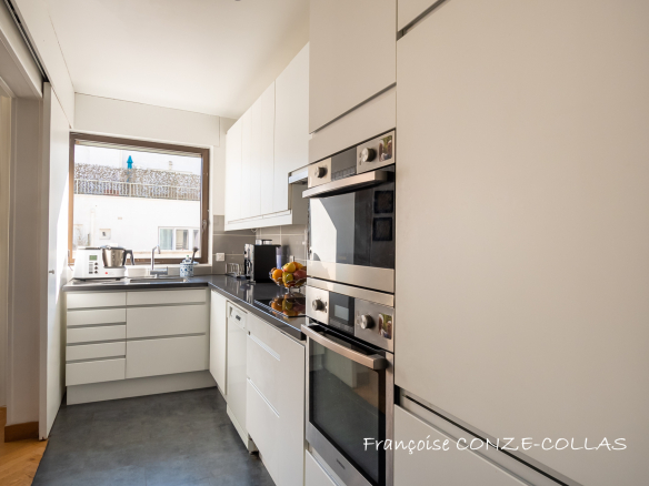 Cuisine moderne d'un appartement lumineux à Levallois-Perret, avec des équipements intégrés et une fenêtre.