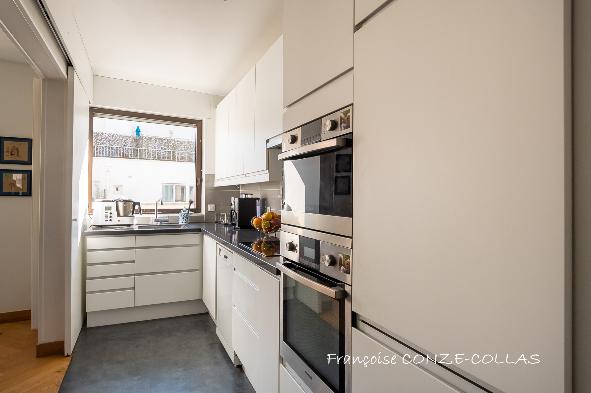 Cuisine moderne d'un appartement lumineux à Levallois-Perret, avec des équipements intégrés et une fenêtre.