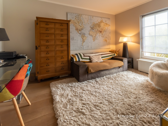 Intérieur d'une maison avec un canapé, un bureau et une carte du monde au mur.