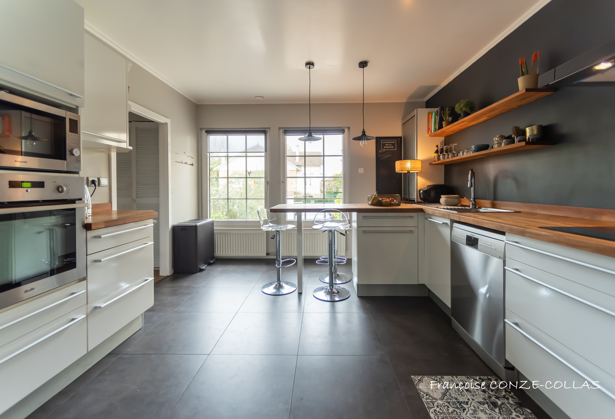 Cuisine moderne à Garches Cuisine moderne avec îlot central et éclairage suspendu, fenêtres donnant sur l'extérieur.