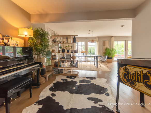 Intérieur d'une maison moderne avec piano, étagère et espace de vie lumineux.