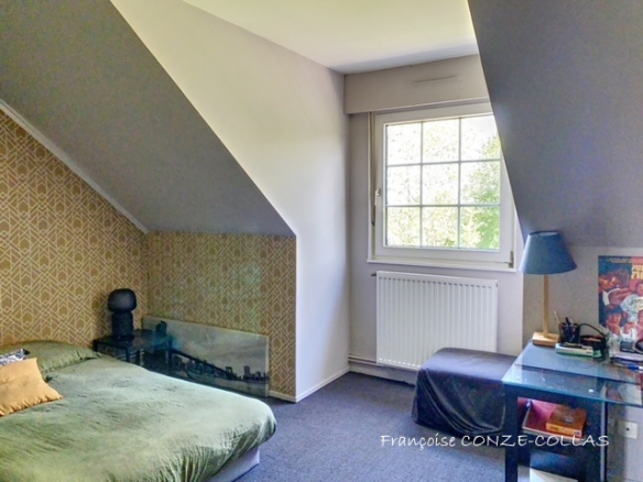 Chambre d'une maison avec un lit, un bureau et une fenêtre donnant sur l'extérieur.