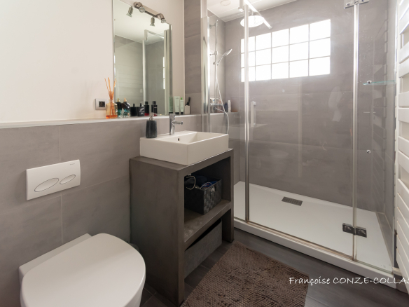 Salle de bain moderne avec douche, lavabo et toilettes.