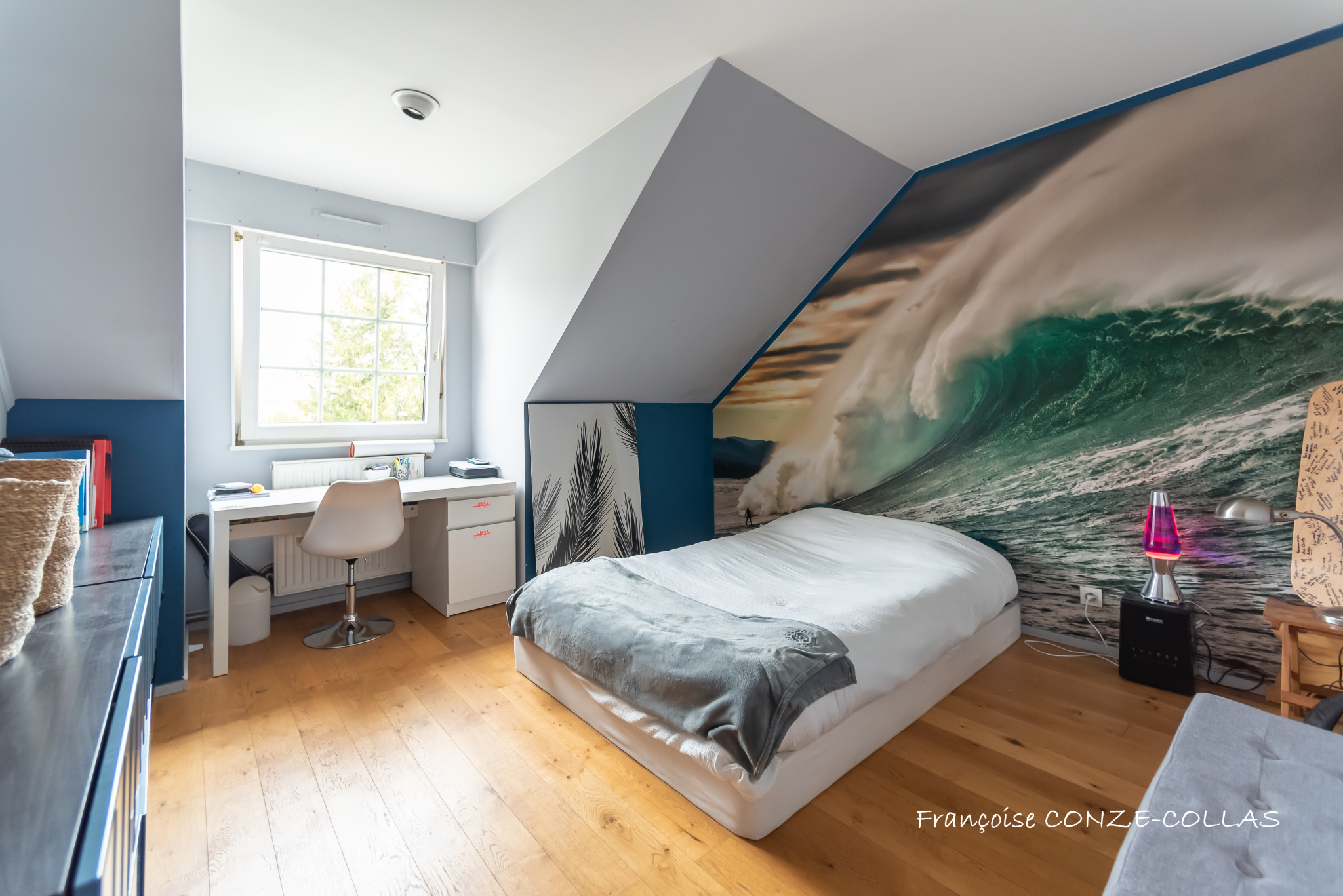 Chambre moderne avec décoration marine Chambre d'une maison avec décor mural représentant une vague, bureau et lit.