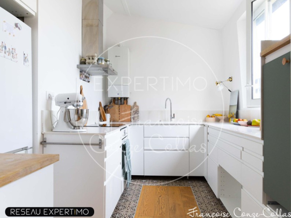 Cuisine moderne dans un appartement ancien rénové à Versailles, avec des éléments en bois et des appareils électroménagers.