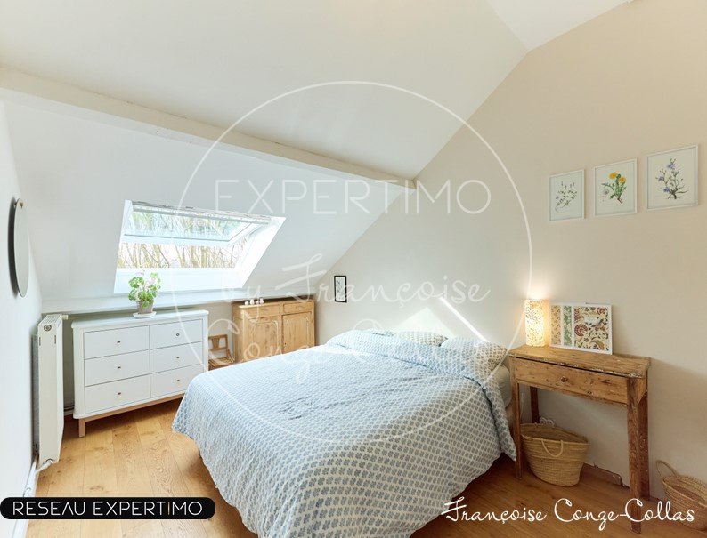 Chambre d'un appartement sous les combles avec fenêtre de toit et décoration simple.