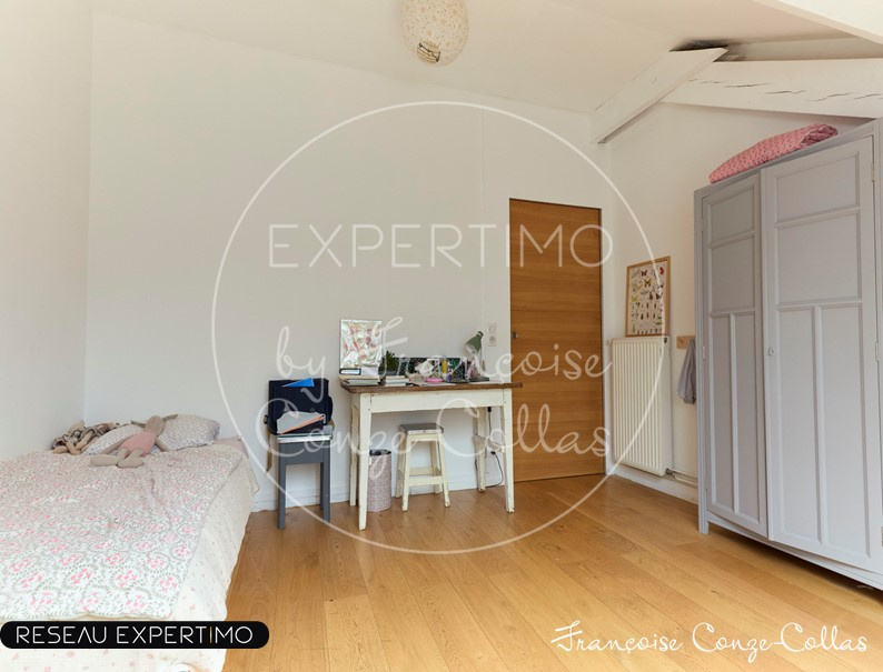 Chambre d'un appartement rénové avec lit, bureau et armoire dans un style ancien.