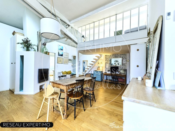 Intérieur d'un appartement rénové avec poutres apparentes et mezzanine, espace de vie lumineux.