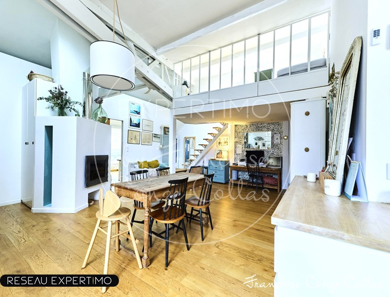 Intérieur d'un appartement rénové avec poutres apparentes et mezzanine, espace de vie lumineux.