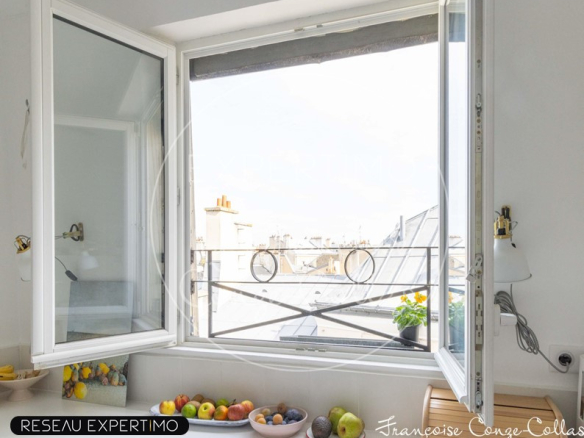 Vue depuis une fenêtre d'appartement avec balcon, fruit sur le rebord, toits de Versailles en arrière-plan.
