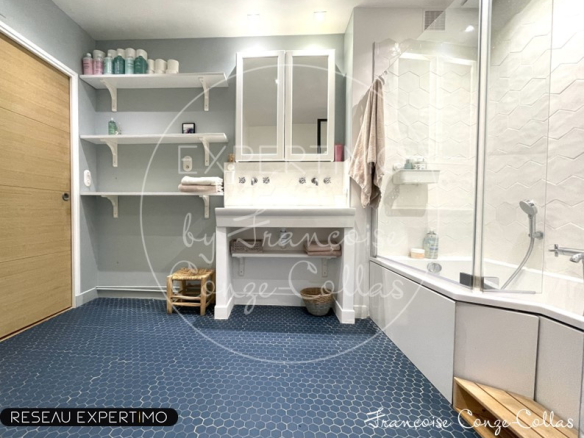 Salle de bain moderne avec douche et double vasque, carrelage hexagonal bleu.