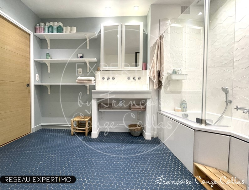 Salle de bain moderne avec douche et double vasque, carrelage hexagonal bleu.