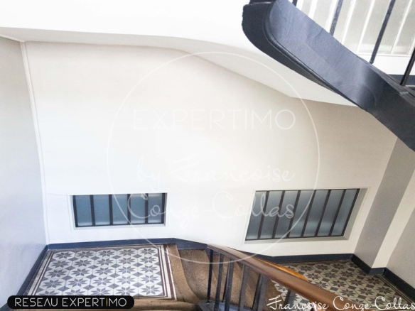 Escalier d'un immeuble ancien avec des carreaux décoratifs et des fenêtres.