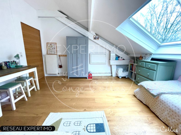 Chambre d'appartement avec poutres apparentes et mezzanine, lumière naturelle.