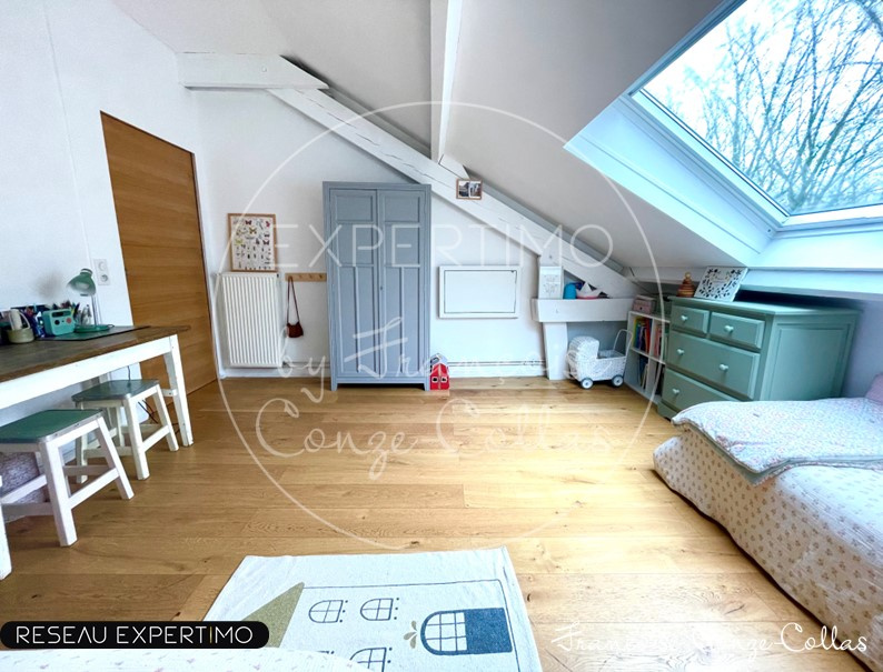 Chambre d'appartement avec poutres apparentes et mezzanine, lumière naturelle.