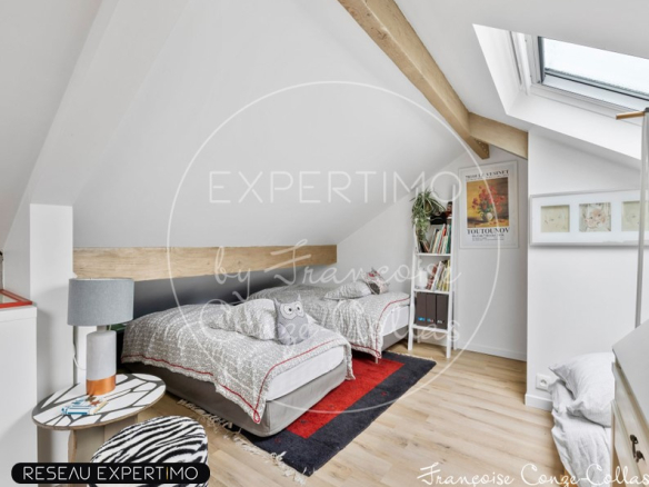 Chambre mansardée avec deux lits simples et décoration moderne.