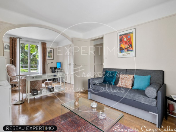 Intérieur d'une maison à vendre avec un salon lumineux et un canapé, fenêtres donnant sur l'extérieur.