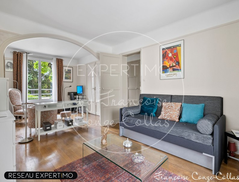 Salon d’une maison à vendre à Marnes-la-Coquette Intérieur d'une maison à vendre avec un salon lumineux et un canapé, fenêtres donnant sur l'extérieur.