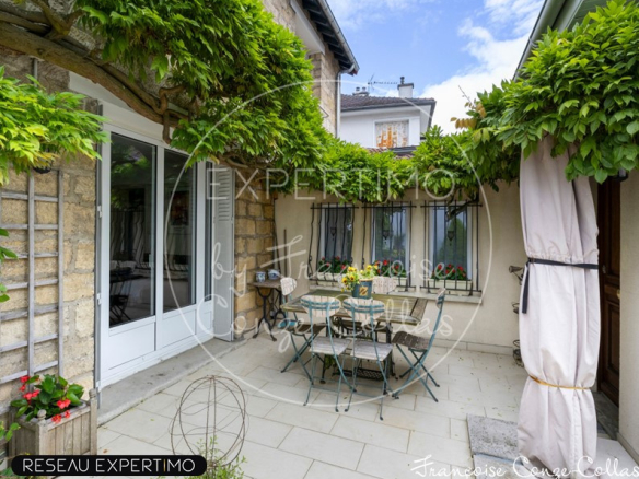 Terrasse d'une maison à vendre avec mobilier de jardin, entourée de verdure.