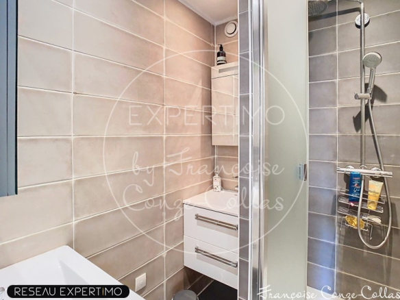 Salle de bain moderne avec douche et lavabo, carrelage gris.