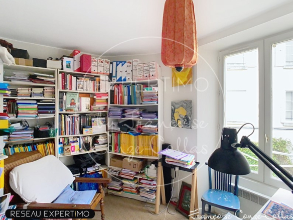 Bureau avec étagères remplies de livres et documents dans un duplex à Versailles.