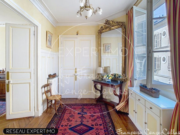 Entrée d'un appartement ancien avec miroir et meuble, parquet en bois, et tapis au sol.