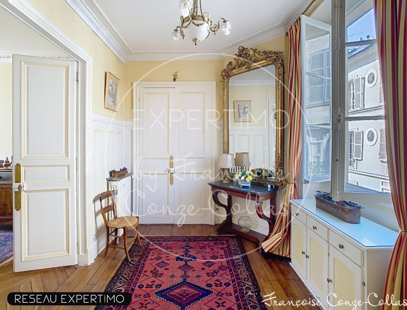 Entrée d’un appartement à Versailles Entrée d'un appartement ancien avec miroir et meuble, parquet en bois, et tapis au sol.