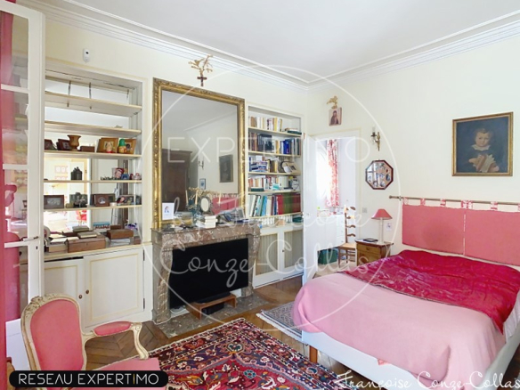 Chambre d'un appartement ancien à Versailles avec un lit, une bibliothèque et un tapis.