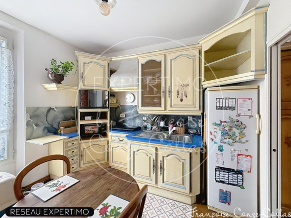 Kitchen of a millstone house with light wood furniture and dining table.