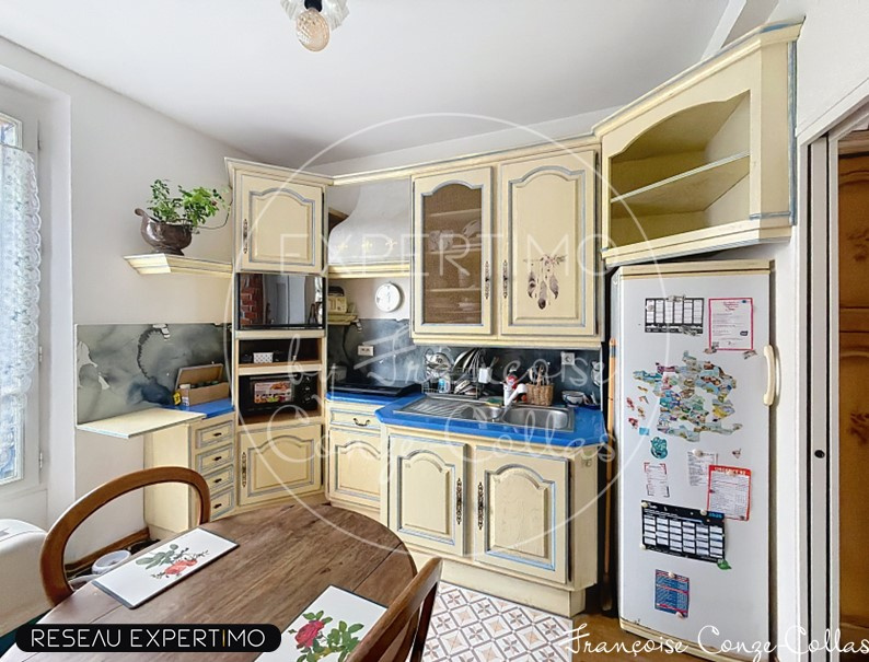 Kitchen of a millstone house with light wood furniture and dining table.