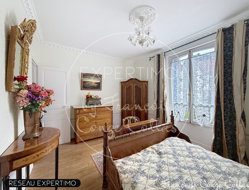 Room with wooden bed, antique wardrobe and windows overlooking a garden.