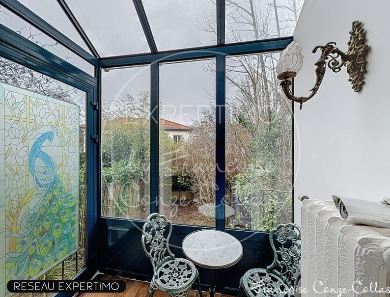 Veranda of a millstone house with stained glass decoration and wrought iron furniture.