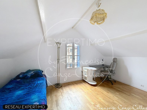 Attic room with a bed and a desk, natural light in Chaville.