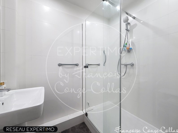 Salle de bain moderne avec douche en verre et lavabo.