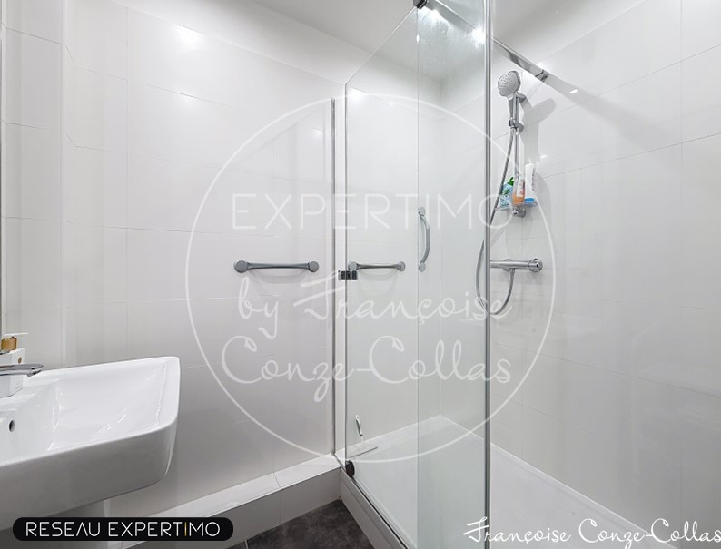 Salle de bain moderne avec douche en verre et lavabo.