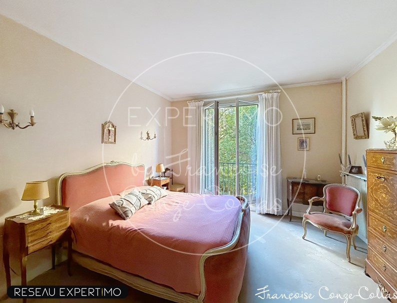 Chambre d'un grand appartement familial à Versailles avec lit et fauteuil.
