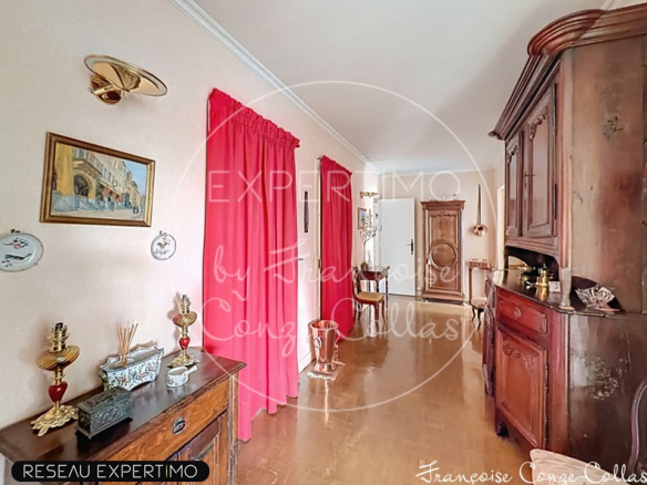 Entrée d'un grand appartement familial avec des murs clairs et des rideaux rouges.