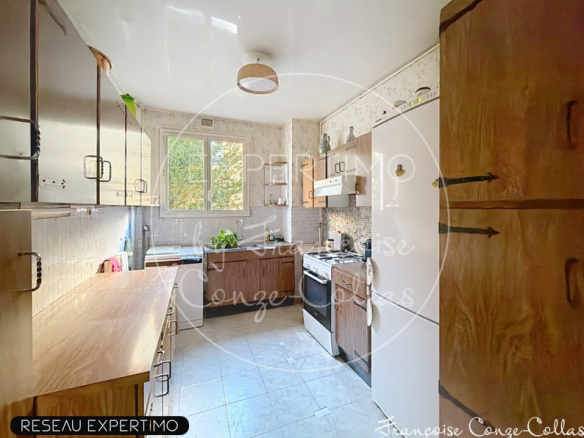 Cuisine spacieuse d'un appartement familial à Versailles avec fenêtres et équipements modernes.