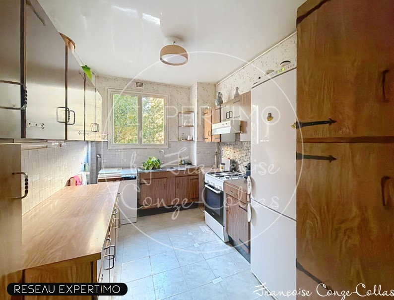 Cuisine spacieuse d'un appartement familial à Versailles avec fenêtres et équipements modernes.