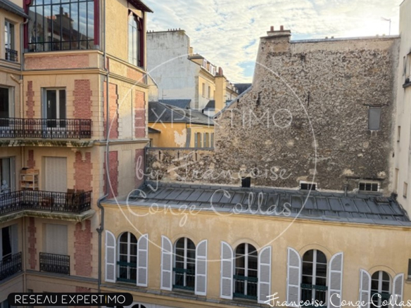 Vue sur des bâtiments historiques depuis un appartement à Versailles, avec balcons et fenêtres.