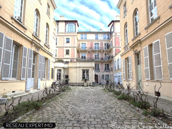 Cour intérieure d'un immeuble historique à Versailles avec pavés et façades anciennes.