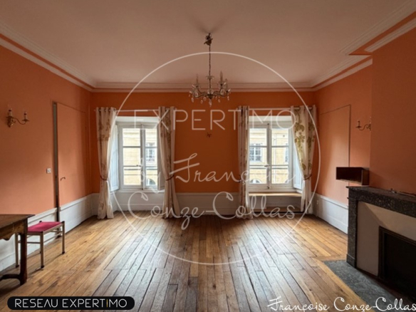 Intérieur d'un appartement de charme à Versailles avec murs orange et parquet en bois.