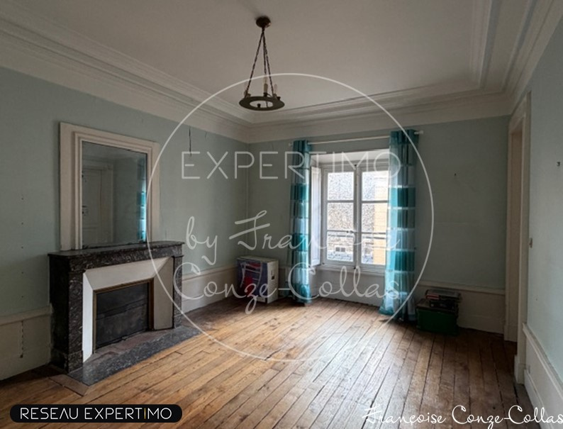 Appartement de charme à Versailles Intérieur d'un appartement à Versailles avec murs clairs et parquet, cheminée en marbre, fenêtres avec rideaux bleus.