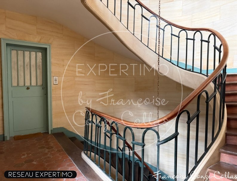 Escalier d’un immeuble historique à Versailles Escalier intérieur d'un immeuble ancien avec rampe en fer forgé et murs en pierre.